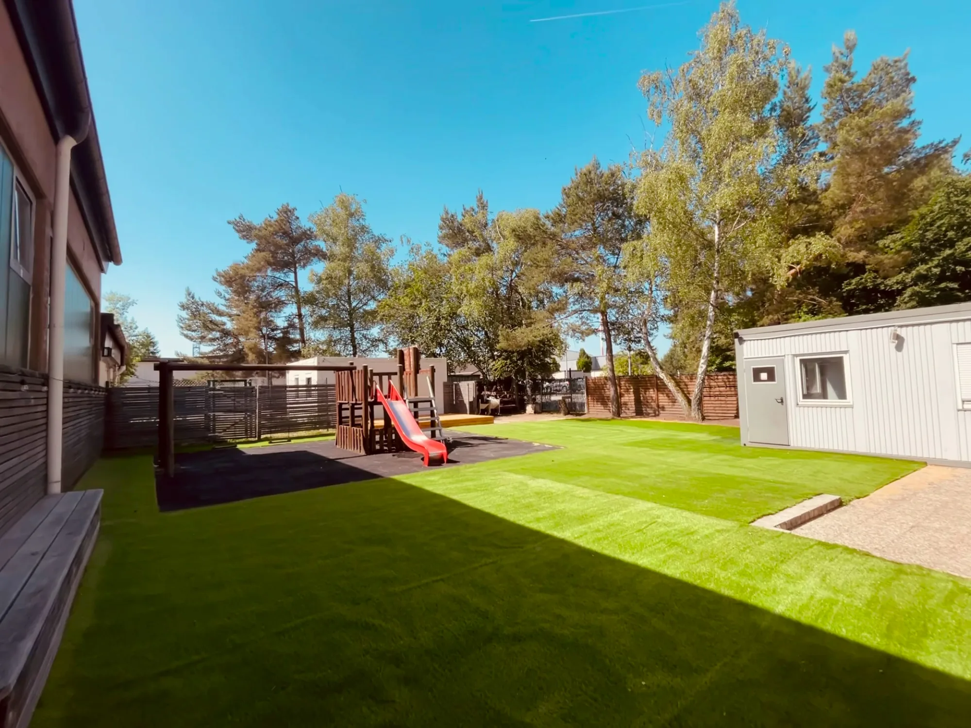 Freshly mown lawn with visible stripes, trees behind it under a blue sky